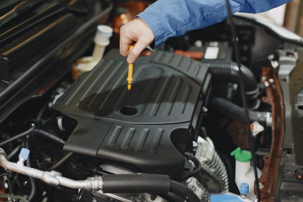 Is Synthetic Oil Better for the Environment? 2 Checking the engine oil level with the dipstick between oil changes